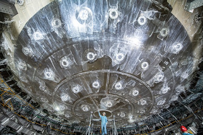 A person stands below an enormous translucent sphere.